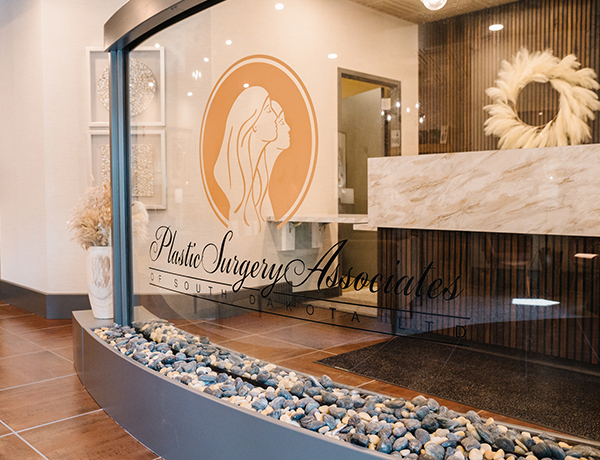 Front office reception area with Plastic Surgery Associates logo on a glass panel.